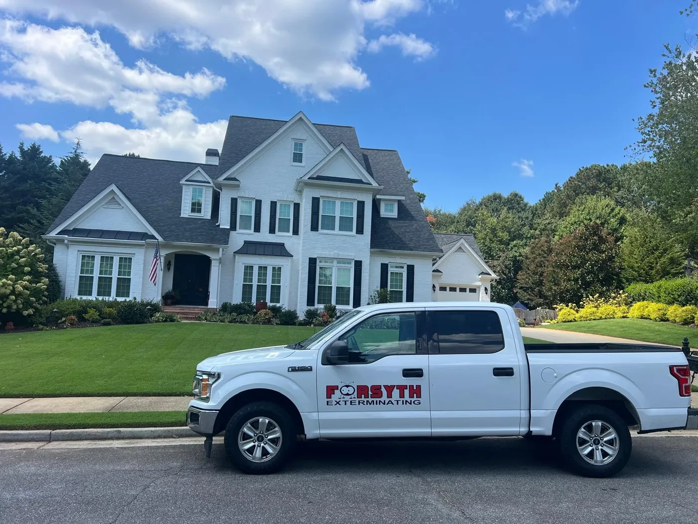 A white Forsyth Exterminating service truck parked in front of a house under a blue sky